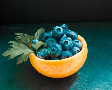 royal blue blueberries in grapefruit peel with a parsley leafの写真素材