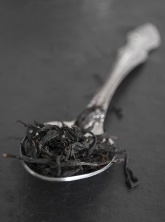 tea leaves in a spoon on a black board in the style of monochrome closeupの写真素材