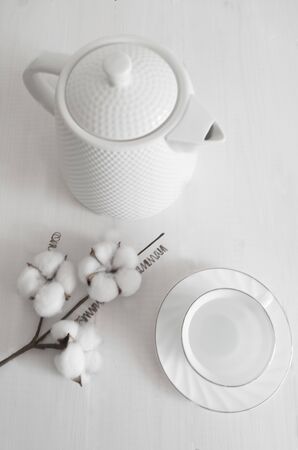 porcelain teapot with a coffee pair and a cotton flower on a table in monochrome top viewの写真素材