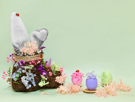 artificial nest in the form of a boot with artificial rabbit ears and three artificial colored eggs