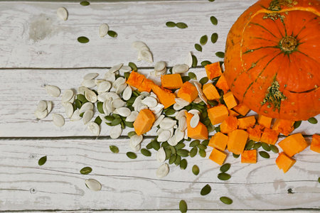 A pumpkin with no insides stands next to a pile of pumpkin pulp and pumpkin seeds.の写真素材