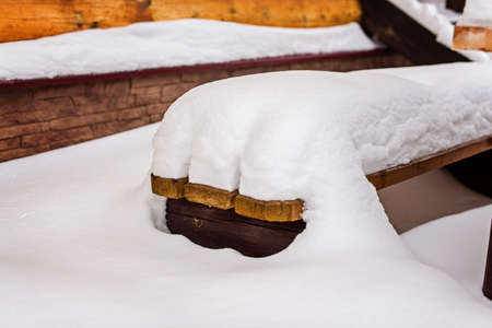 A huge snowdrift on a wooden bench. Heavy snowfall. Winter cycloneの写真素材