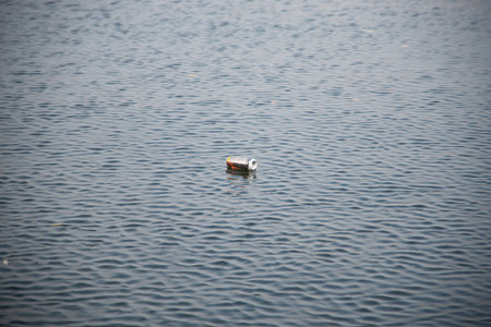 an empty aluminum or iron can floating in the river. Environmental pollution. Garbage in the water.の写真素材