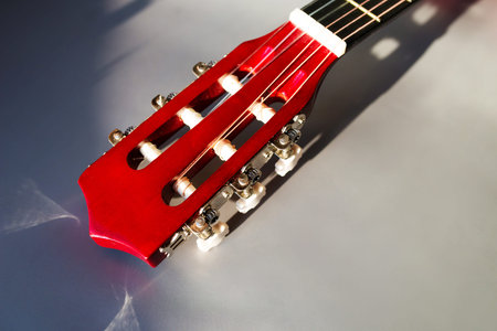 A part of red wooden classic guitar. Six strings