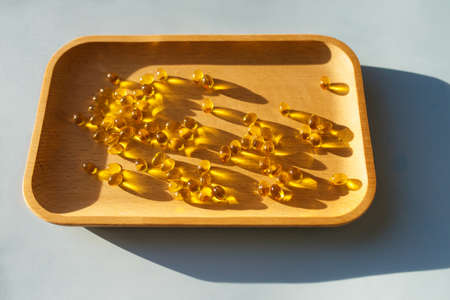 Vitamin d3 gel capsules on a wooden tray. solar vitaminsの写真素材