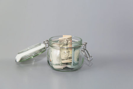 American dollars in a glass jar. Banknotes in a piggy bank. Save money. Financial concept