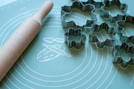 cookie cutters and a rolling pin for dough are on a silicone matの写真素材