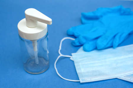 Medical mask, blue gloves and dispenser on a blue backgroundの写真素材