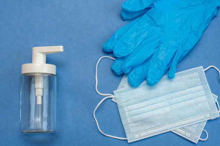 Medical mask, blue gloves and dispenser on a blue backgroundの写真素材
