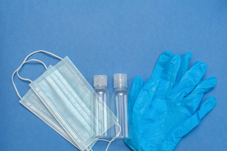Medical mask, blue gloves and two bottles on a blue background