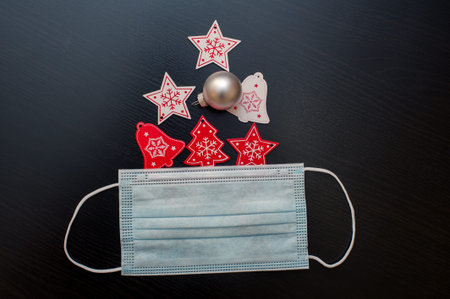 Christmas decorations and face mask on black background