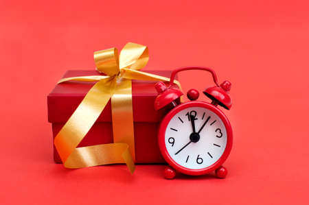 Red alarm clock and red gift box on red backgroundの写真素材