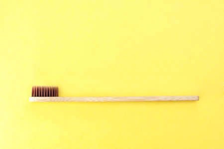 Bamboo toothbrush on a yellow background. Top view, space for text.の写真素材