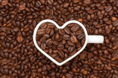Coffee beans. White heart mug filled with coffee beans on coffee beans background