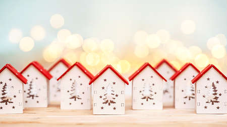 Small Christmas houses on a background of defocused lights. Christmas and New Years celebration concept at homeの写真素材