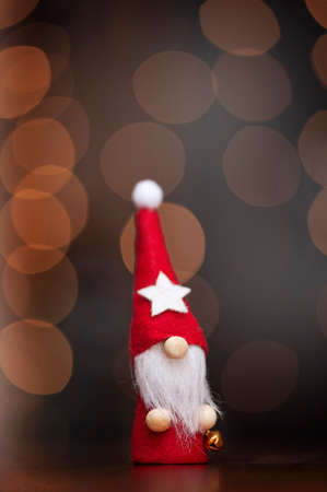 Christmas gnome in a red hat on a dark background of defocused lights. Vertical photoの写真素材