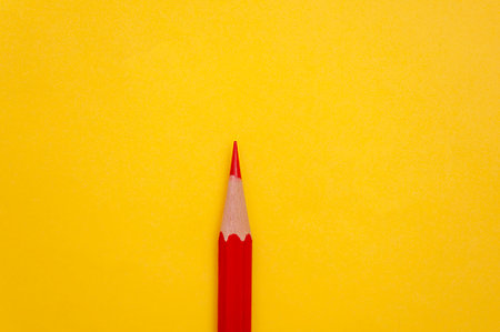 Minimalist background red pencil on yellow background with copy spaceの写真素材