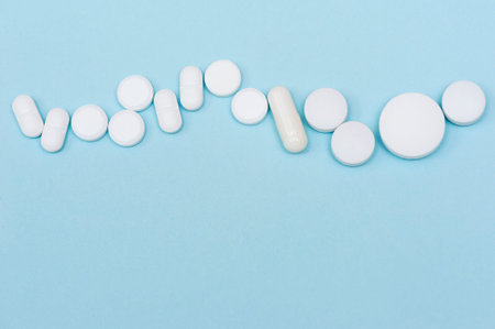 Various white health pills and on a blue background