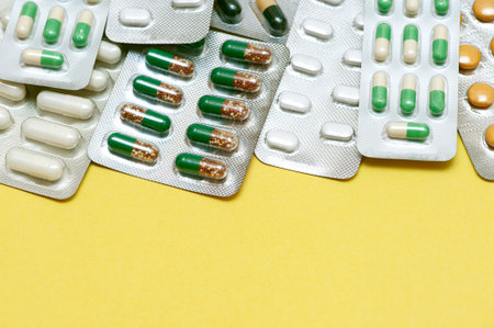 Colorful capsules with antibiotics in a blister pack on a yellow background. Top view, flat lay,...