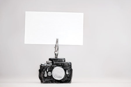 Business card holder in the form of a camera with a blank business card on a neutral background