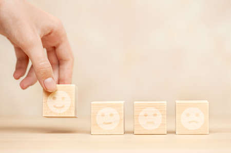 Man's hand holds a positive emotion on the block. Concept of quality evaluation, feedback or positive thinkingの写真素材