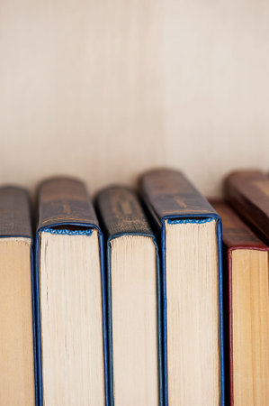A small stack of hardback books stands on a table, Vertical photo