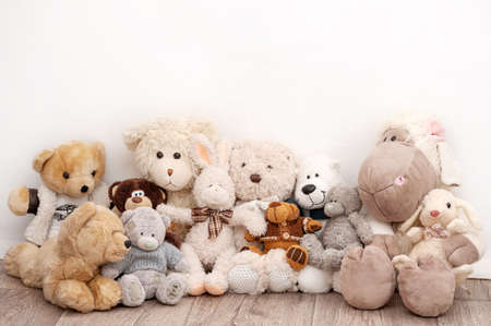 Many soft toys are sitting on the background of a white wallの写真素材