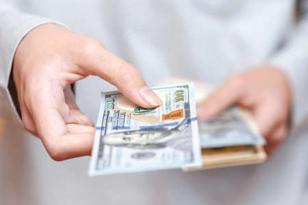 The hand holds out a banknote. Concept of cash, currency, economyの写真素材