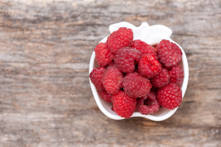 Seed ripe raspberries in a cup on a wooden background. copy spaceの写真素材