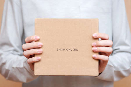 The courier is holding a cardboard box. Fast and free shipping.の写真素材