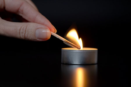 Close up of woman hand lighting candles in the dark night at homeの写真素材
