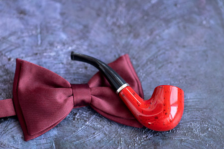 Red bow tie and smoking pipe on a blue background. Happy father's day concept. flat lay