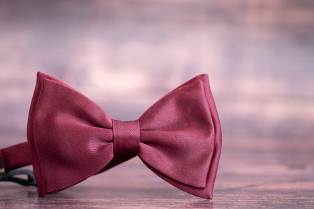 A maroon bow tie on a wooden tableの写真素材