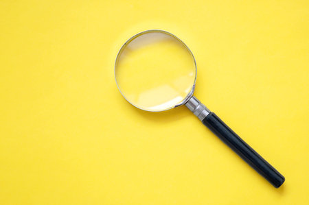 A yellow background with question marks and a magnifying glassの写真素材