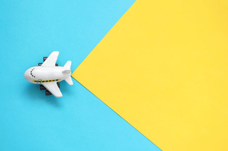 A toy airplane on a yellow and blue background. Empty place for pasting text
