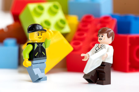 Two LEGO mini-characters close-up against the background of LEGO bricks. Educational children's toys.のeditorial素材