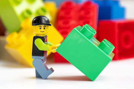 LEGO mini character worker carries a Lego brick. Educational children's toysのeditorial素材