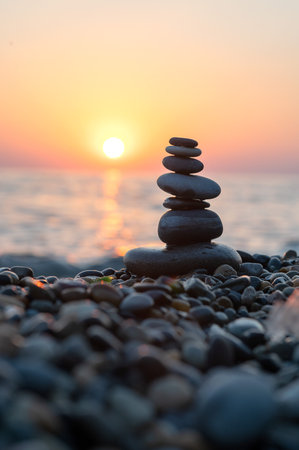 Stack of pebble stones on sea beach at sunset. Zen concept