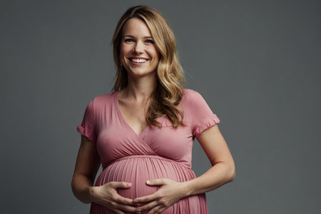 Pregnant woman in a pink dress on a gray background.の素材