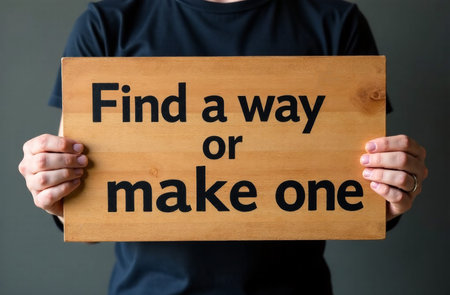 Midsection of man holding signboard with text Find a way to make oneの素材
