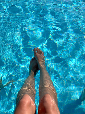 Legs of a young woman in a swimming pool on a sunny dayの写真素材