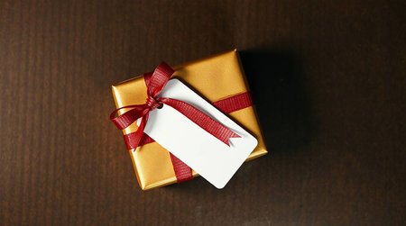Gift box with red ribbon and tag on the wooden background.の素材