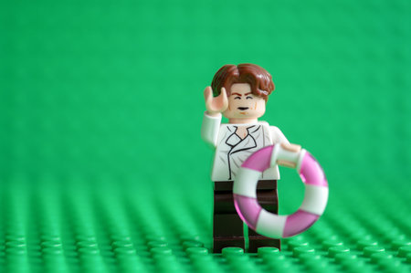 Lego Minifigure Businessman and lifebuoy on green backgroundのeditorial素材