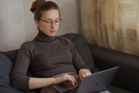 The beautiful woman is sitting on the sofa. Study at home