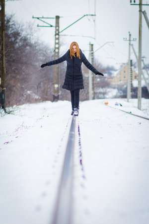 Young beautiful girl near rails in winter.