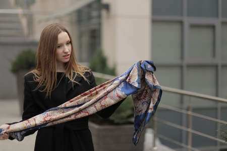 The girl in black coat in the city. Shawl, handkerchief on a person.の写真素材