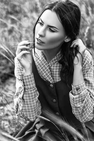 outdoor portrait of a beautiful brunette woman in blue dress in the field. Black and white photoの写真素材
