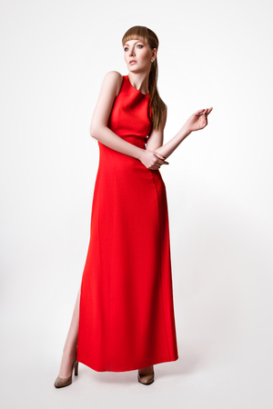 beautiful woman model posing in simple elegant red dress in the studio on white backgroundの写真素材