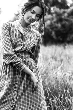 outdoor portrait of a beautiful brunette woman in dress with flowers in her hair in the field. Black and white photoの写真素材