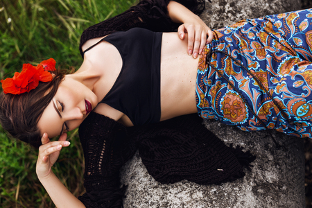 fashion outdoor portrait of a beautiful brunette woman with flowers in hair in the fieldの写真素材